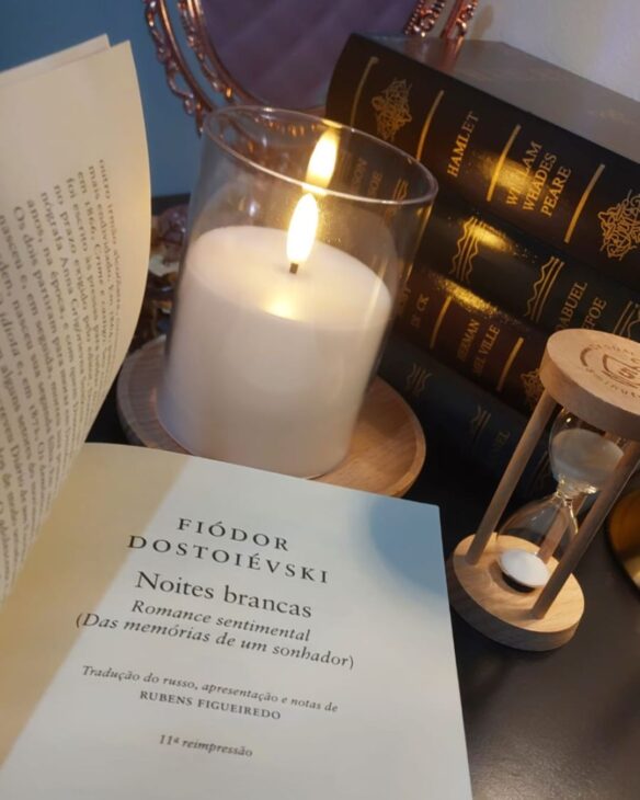 contracapa do livro noites brancas com uma vela compondo o cenário, além de livros antigos