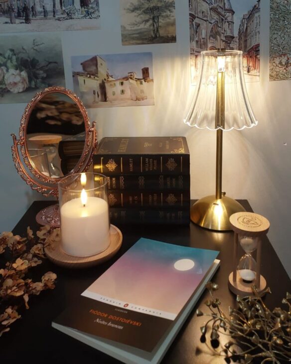 livro noites brancas de doistoiéviski em uma cômoda ao lado de uma vela, um espelho e um abajur