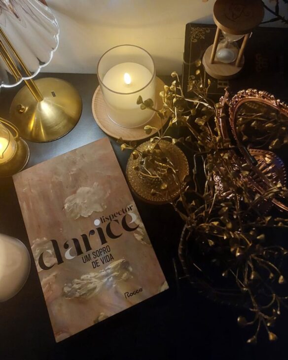 livro um sopro de vida, da clarice lispector, cercado por um abajur e uma vela